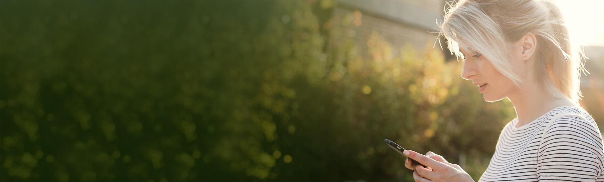 Header Image, woman looking at smart phone outdoors